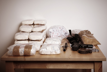 Lot of drugs seized by police on table with weapons