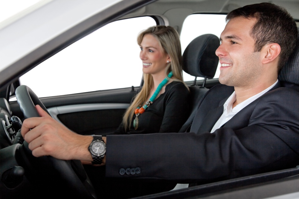 Happy couple driving a car isolated over a white background