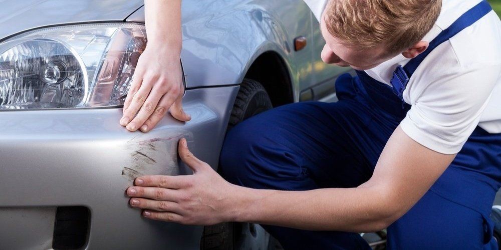 Mechanic assess damage on car