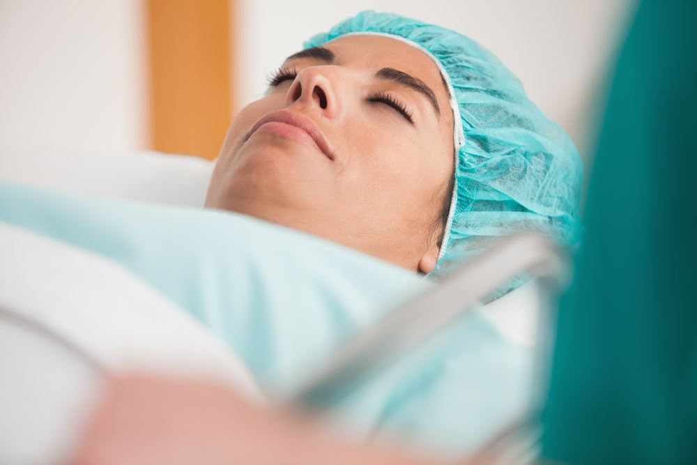 Patient lying on gurney before surgery in hospital corridor