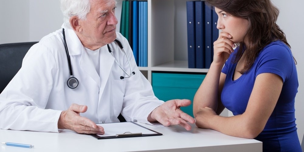 Senior male doctor talking to worried woman