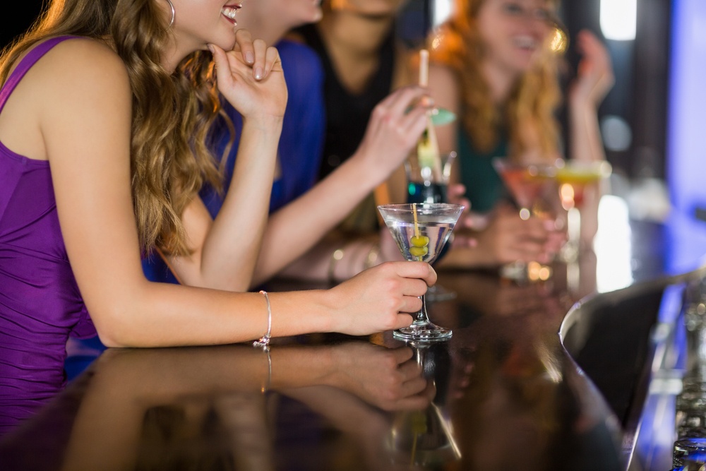 Smiling woman having glass of cocktail in bar