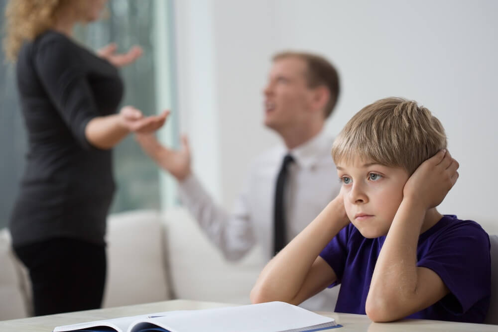 Boy covering ears while parents are fighting