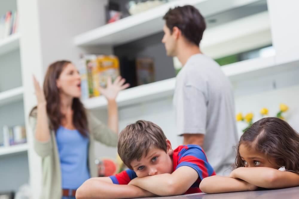 Couple fighting behind children